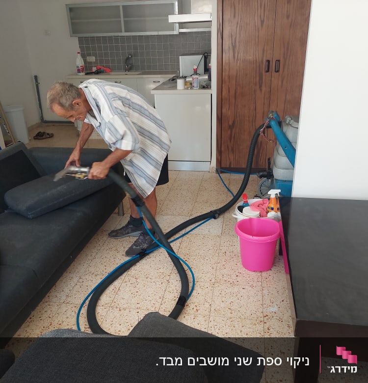 אדם מנקה ספה עם מכונת ניקוי ושואב אבק